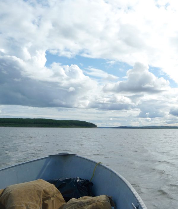 Boat on water in foreground with a cloudy, blue sky in the background