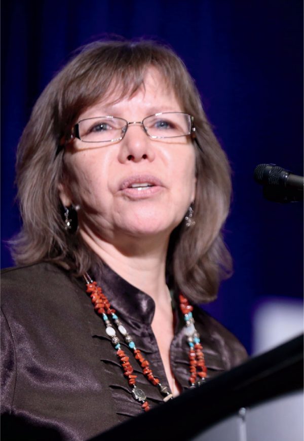 Close-up of woman speaking in brown shirt and beaded necklace