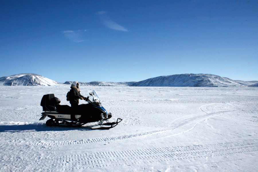 Person riding a snowmobile across snow covered land