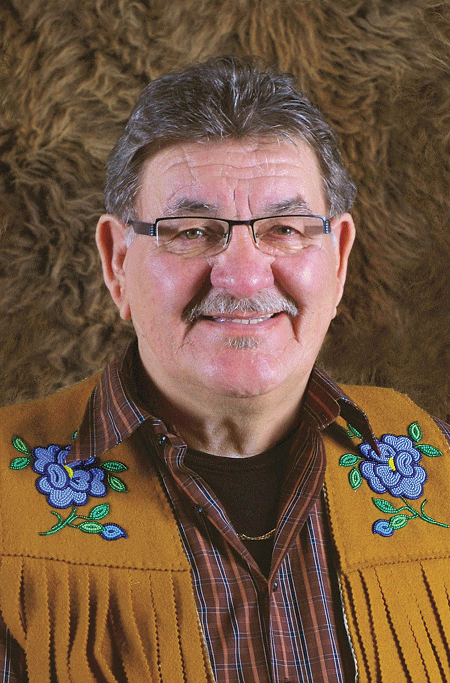 man with glasses and moustache wearing a brown coat with flowers on the shoulders
